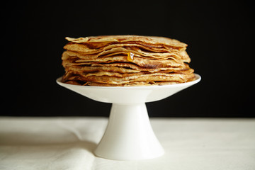Crepes cake with orange jam and honey on white cake stand. Pancake breakfast concept
