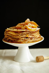 Crepes cake with orange jam and honey on white cake stand. Pancake breakfast concept