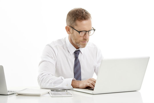 Middle Aged Business Man Portrait. Successful Businessman Sitting At Desk With Laptops And Working. Isolated On White Background.  