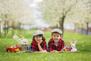 Two children, boy brothers, having fun with easter eggs in the park