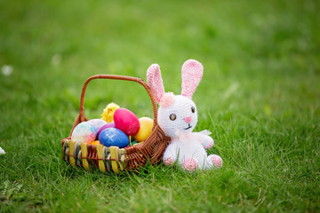 Little teddy bear toy and a basket of eggs colored for Easter