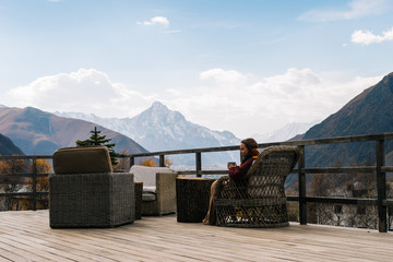 a young girl travels, sits on a veranda and enjoys a view of the mountains