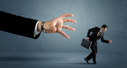 Business man running away from a huge hand concept