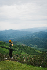 Woman talking picture of landscape on Doi Chang Moob viewpoint. This place locateed in Chiang Rai, Thailand.