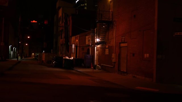 Camera pans to creepy alley at night in downtown city
