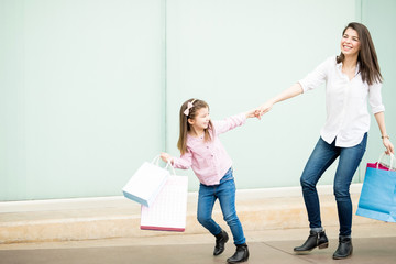 Obraz premium Beautiful little girl pulling mother outside shopping mall