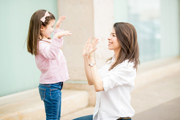 Happy mother and daughter playing with hands