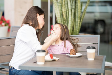 Mother wiping daughter's mouth at restaurant