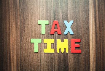 Colorful word Tax Time on wooden background.