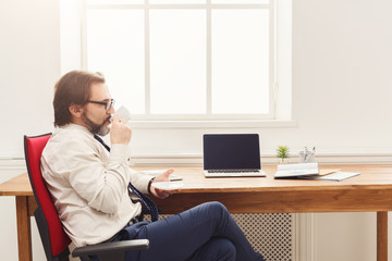 Serious businessman having coffee break in office