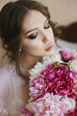 Portrait of beautiful young brunette woman with closed eyes and big seductive lips, with bouquet of flowers in her hands