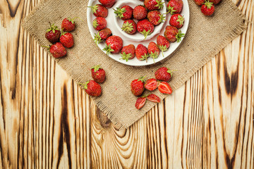 red strawberries in bowl on a wooden background