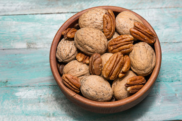 Tasty pecan  and walnuts  in wooden bowl on the old background.