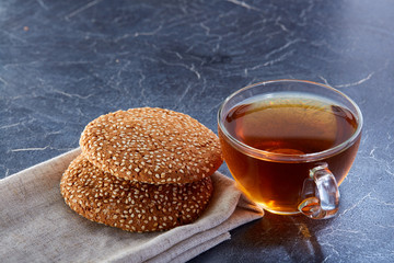 Shallow depth of field photo of a glass cup of black tea with brownies on a dark greyish marble background.
