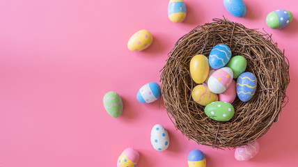 Colorful easter egg and nest on pink pastel color background with space.