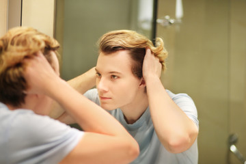 young man looking in the mirror and combing his hair