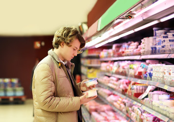 Man shopping in supermarket, reading product information