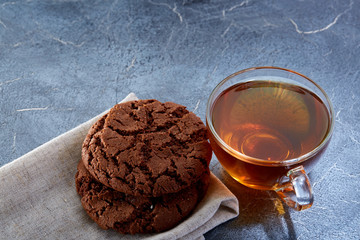 Shallow depth of field photo of a glass cup of black tea with brownies on a dark greyish marble background.