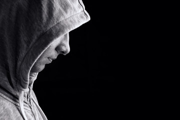 Athlete in hood on a black background. Drops of sweat on the face of the male athlete in the hood.