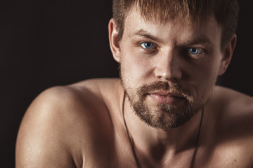 Fototapeta premium Portrait of a handsome young man on a black background. Male face closeup