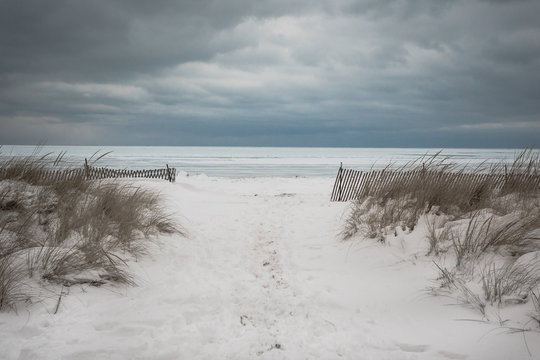 Snow covered entry to beach with wild grass