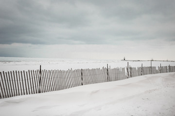 Wooden fence running down snowy beach