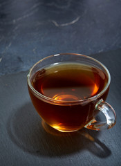 Glass cup of tea isolated on dark marble background, close-up