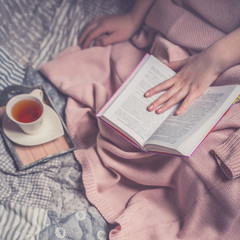 Naklejka premium Close up lifestyle soft image of pretty young woman sitting on her cozy bed and making notes to her diary. Fall season mood. Bright colors.