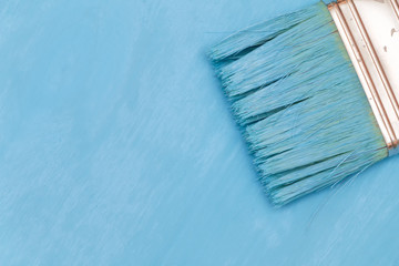 Staining the wooden surface with blue paint using a paint brush