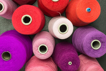 cones of wool and cotton yarn in red, pink and violet