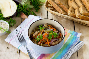 Warm salad with boiled meats and grilled vegetables (eggplant, carrots, paprika) он the kitchen wooden table.