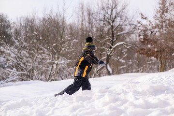 Fototapeta na wymiar Little boy runs through snow