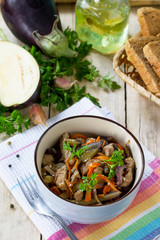 Warm salad with boiled meats and grilled vegetables (eggplant, carrots, paprika) он the kitchen wooden table.