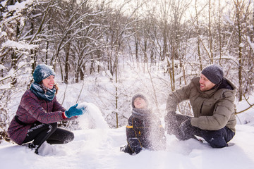 Fototapeta na wymiar Happy family throw snow in winter forest