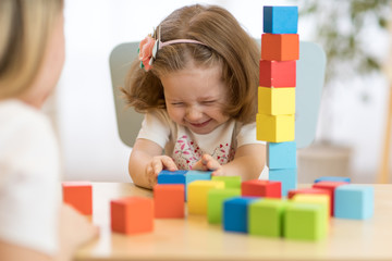 Funny kid and mom playing together with educational toys