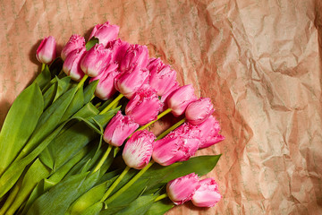 Fresh flower composition, bouquet pink tulips on craft paper background. Valentine, Women's, 8 march, birthday, mother's day present. Copy space, close up, top view.