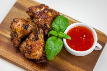 Chicken wings with sweet chilli sauce on the wooden cutting board