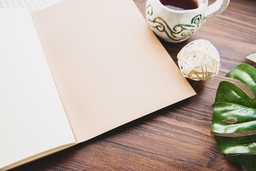 A stylish notebook, a cup of tea and a philodendron leaf