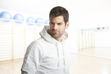 Young man at the gym. Young male personal trainer wearing hoodie while standing at the gym before workout. 