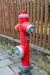 A Red water hydrant in the middle of the footpath