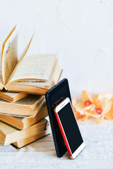 a stack of old books, phone, and e-book, concept of the development of technology, gadgets and love to read on a white background