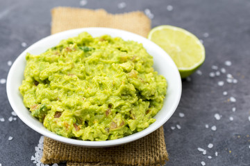 Bowl of guacamole on black wooden background.