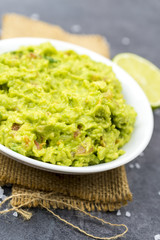 Bowl of guacamole on black wooden background.