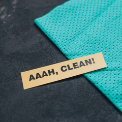 Cleaning house or office concept. Blue cleaning rag, AAAH, CLEAN inscription on a dark concrete background. Top view, closeup