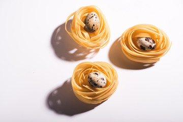 Three italian pasta nests isolated on white background with quail egg