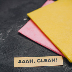 Cleaning house or office concept. Red and yellow cleaning rags, AAAH, CLEAN inscription on a dark concrete background. Top view, closeup