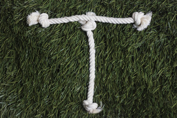 Rope alphabet on grass. Letter T