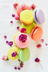Delicate Fresh Colorful French Macaroons In Pastel Colors With Flowers Roses On A Light Textile Background