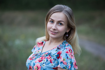 Portrait of young beautiful smiling woman in flower vintage dress on the background of green grass.