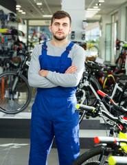 Portrait of young repairman standing near cycle in bicycle store
